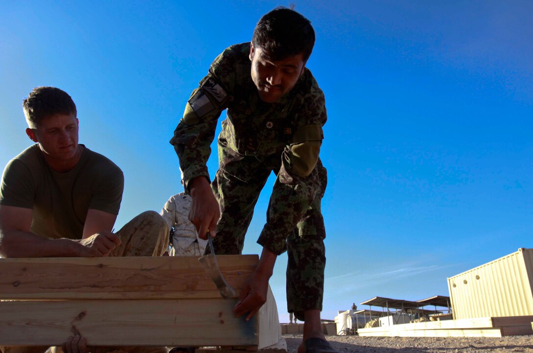 Cpl. Michael Wimberley, an Embedded Partnering Team mentor with Combat Logistics Battalion 3, 1st Marine Logistics Group (Forward) watches as an Afghan National Army soldier helps build a combat operations center aboard Camp Garm-sher, Afghanistan, Dec. 10. The Marines of CLB-3's EPT are currently mentoring ANA soldiers to operate independent from coalition forces.