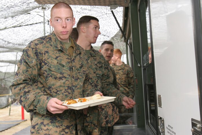 Lance Cpl. Richard R. Aubin, Marine Wing Support Squadron 171 electrician, holds his tray of hot chow at the field expedient mess hall during the W.P.T. Hill Memorial award evaluation Saturday set up at Penny Lake. The mess hall was set up under camouflage netting.