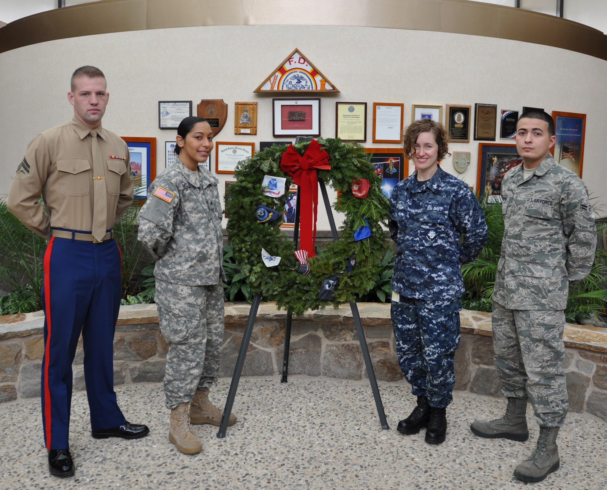 Marine Cpl. Matthew Duerr, Army Sgt. Mariangelica Aviles, Navy Petty Officer 2nd Class Jennifer Howell and Air Force Airman 1st Class Vincent Montoya pose with the Wreath they placed in the atrium of Air Force Mortuary Affairs Operations at noon on Dec. 11, 2010. The ceremony, honoring veterans, takes place each year on the second Saturday in December. It is sponsored by Wreaths Across America, a nonprofit organization whose mission is to remember, honor and teach. (U.S. Air Force photo/Christin Michaud)