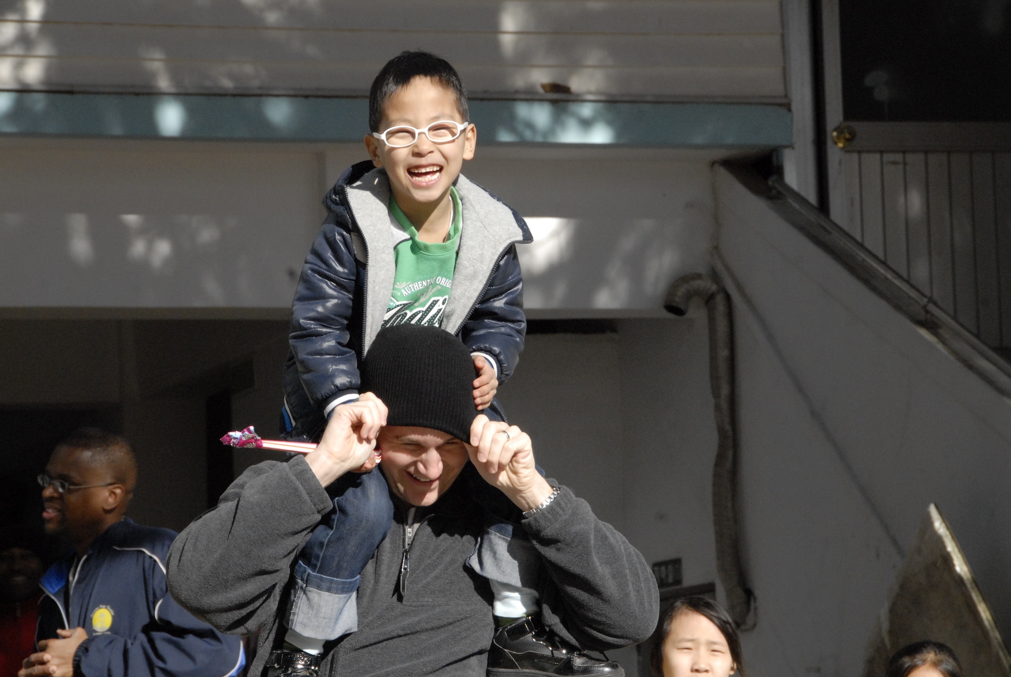 KUNSAN AIR BASE, Republic of Korea -- Tech. Sgt. Jeremy Fields, 8th Civil Engineer Squadron, carries Pak Young-do on his shoulders at the Il Mag Won orphanage Dec. 11.  Volunteers from the base chapel coordinated a holiday party for the children at the orphanage, where volunteers donated time, gifts, food and more to the children to celebrate the holiday season.  (U.S. Air Force photo/Capt. Sheryll Klinkel)