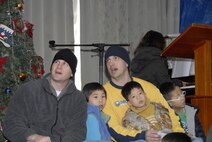 KUNSAN AIR BASE, Republic of Korea -- Tech. Sgts. Jeremy Fields (left) and Pete Rollins (right) sing Christmas carols with children from the Il Mag Won orphanage Dec. 11.  Sergeant Fields, Rollins and other Wolf Pack members from the base chapel coordinated a holiday party for the children at the orphanage, where volunteers donated time, gifts, food and more to the children.  (U.S. Air Force photo/Capt. Sheryll Klinkel)