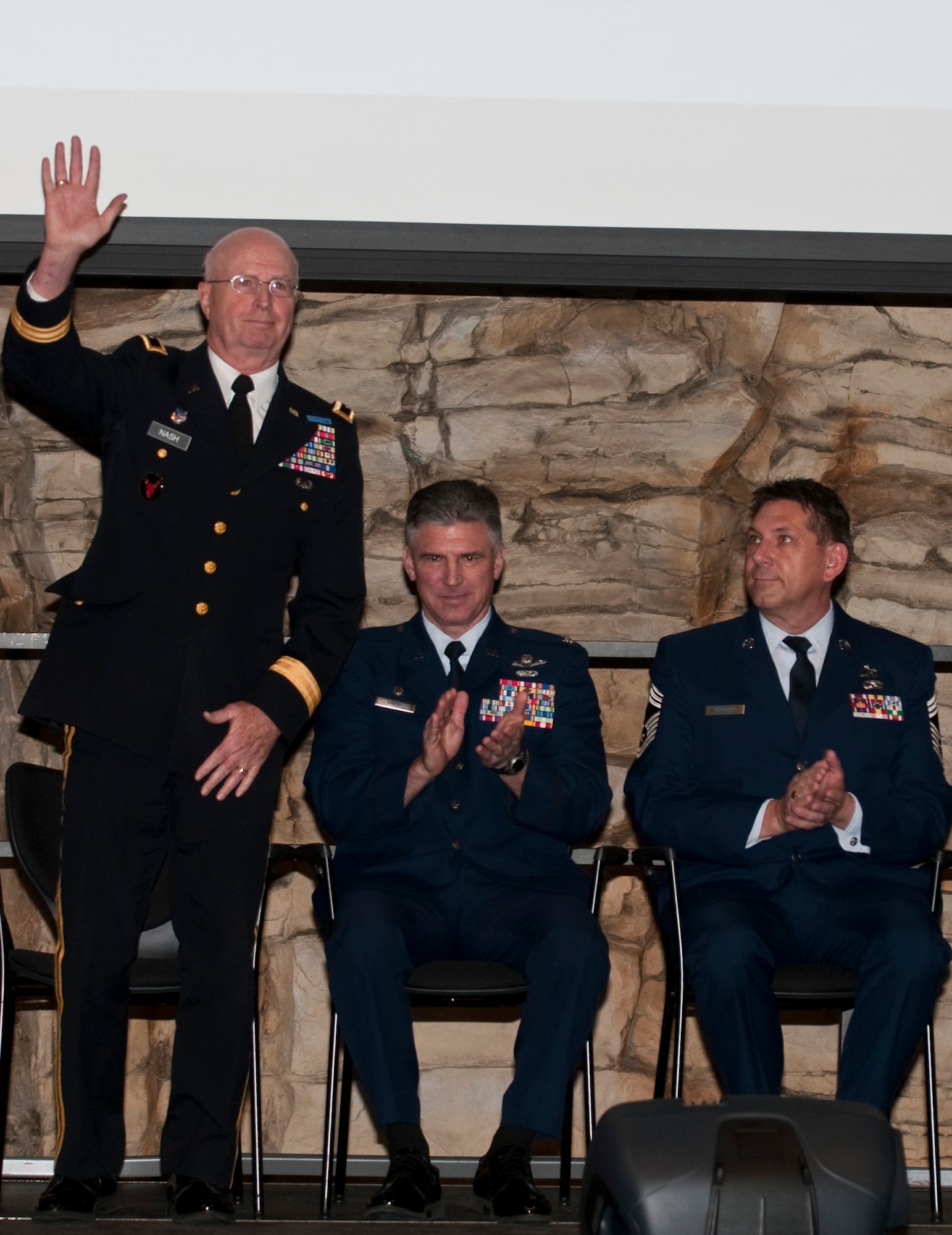 The Adjutant General of Minnesota, Maj. Gen. Rick Nash, waves from the stage during the 133rd Airlift Wing Recognition Ceremony Dec. 11, 2010 in St. Paul, Minn. Sitting alongside him are 133rd Airlift Wing Commander Col. Greg Haase and 133rd Airlift Wing Acting Command Chief, Chief Master Sgt. Ray Kennedy.
USAF official photo by Tech. Sgt. Erik Gudmundson