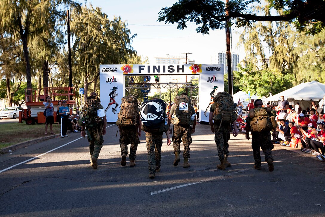 Marines with Aircraft Rescue Firefighting, Marine Corps Air Station Kaneohe Bay, Hawaii, and the School of Infantry West — Detachment Hawaii, complete the final stretch of the 2010 Honolulu Marathon, Dec. 12, 2010. For the second year in a row, the Marines hiked the 26.3-mile marathon with boots, camouflage trousers and 65-pound packs to raise money for wounded Marines and sailors at Wounded Warrior Battalion West — Detachment Hawaii, on Marine Corps Base Hawaii. “In the end, the wounded warriors were who we were there for,” said Chicago native Sgt. Fernando Camacho, a firefighter with ARFF. “Ultimately, our goal was to raise money for the wounded Marines and sailors, but it didn’t matter how much we did or didn’t raise — it was that we were there supporting them.”