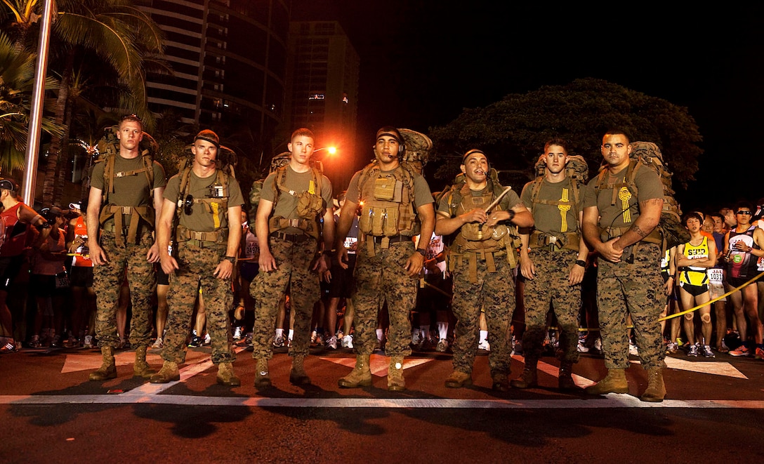 Sharply contrasting the bright, buzzing collage of more than 22,000 competitors at the 2010 Honolulu Marathon, firefighters from Aircraft Rescue Firefighting, Marine Corps Air Station Kaneohe Bay, Hawaii, and a black belt Marine Corps Martial Arts Program instructor from the School of Infantry West — Detachment Hawaii, stand ready at the marathon’s starting line, Dec. 12, 2010. For the second year in a row, the Marines hiked the 26.3-mile marathon with boots, camouflage trousers and 65-pound packs to raise money for wounded Marines and sailors at Wounded Warrior Battalion West — Detachment Hawaii, on Marine Corps Base Hawaii.