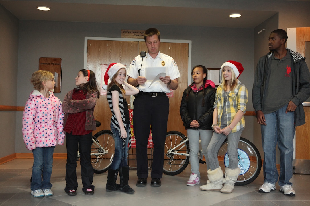 MARINE CORPS BASE CAMP LEJEUNE, N.C. - Glenn Zurek, the assistant chief of Fire Prevention with Fire and Emergency Services Division, Department of Public Safety, Marine Corps Base Camp Lejeune, reads off the awards, as school children that recently won Fire Safety Week contests await their award at the Fire and Emergency Services Division main lobby aboard the base, Dec. 14. Prizes includes free coupons, bikes and an Xbox.