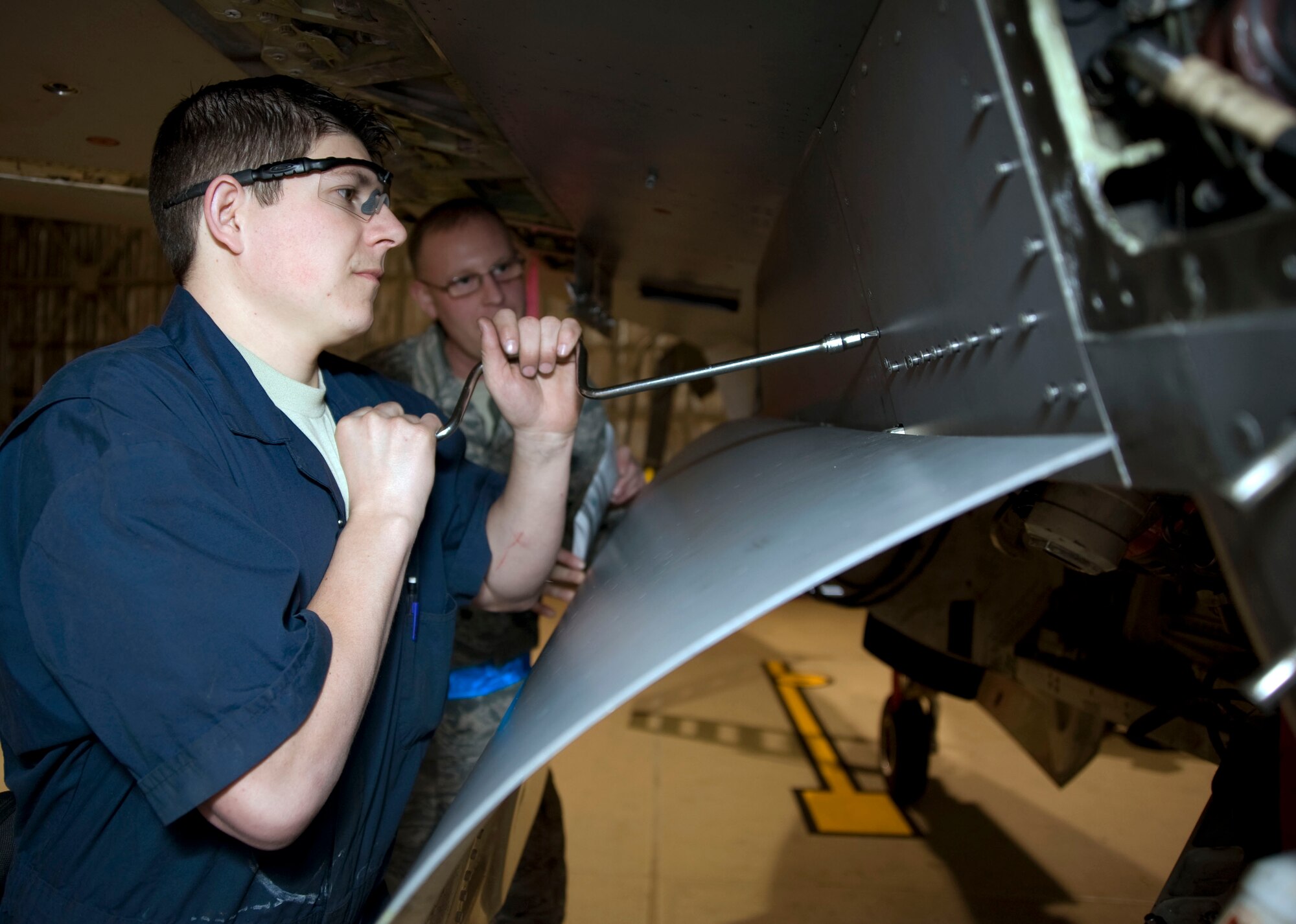 U.S. Air Force Staff Sgt. Travis Scates, left, 35th Maintenance Squadron, removes a panel on an F-16 Fighting Falcon during routine maintenance check while Tech. Sgt.  Kristopher Konicek, left, 35th Maintenance Group, Quality Assurance flight,  is performing a phase inspection at Misawa Air Base, Japan, Dec. 10, 2010. The QA flight performs quality verification inspections, special inspections and personnel evaluations on maintainer assigned to the group. (U.S. Air Force photo by Tech. Sgt. Russell McBride/Released)