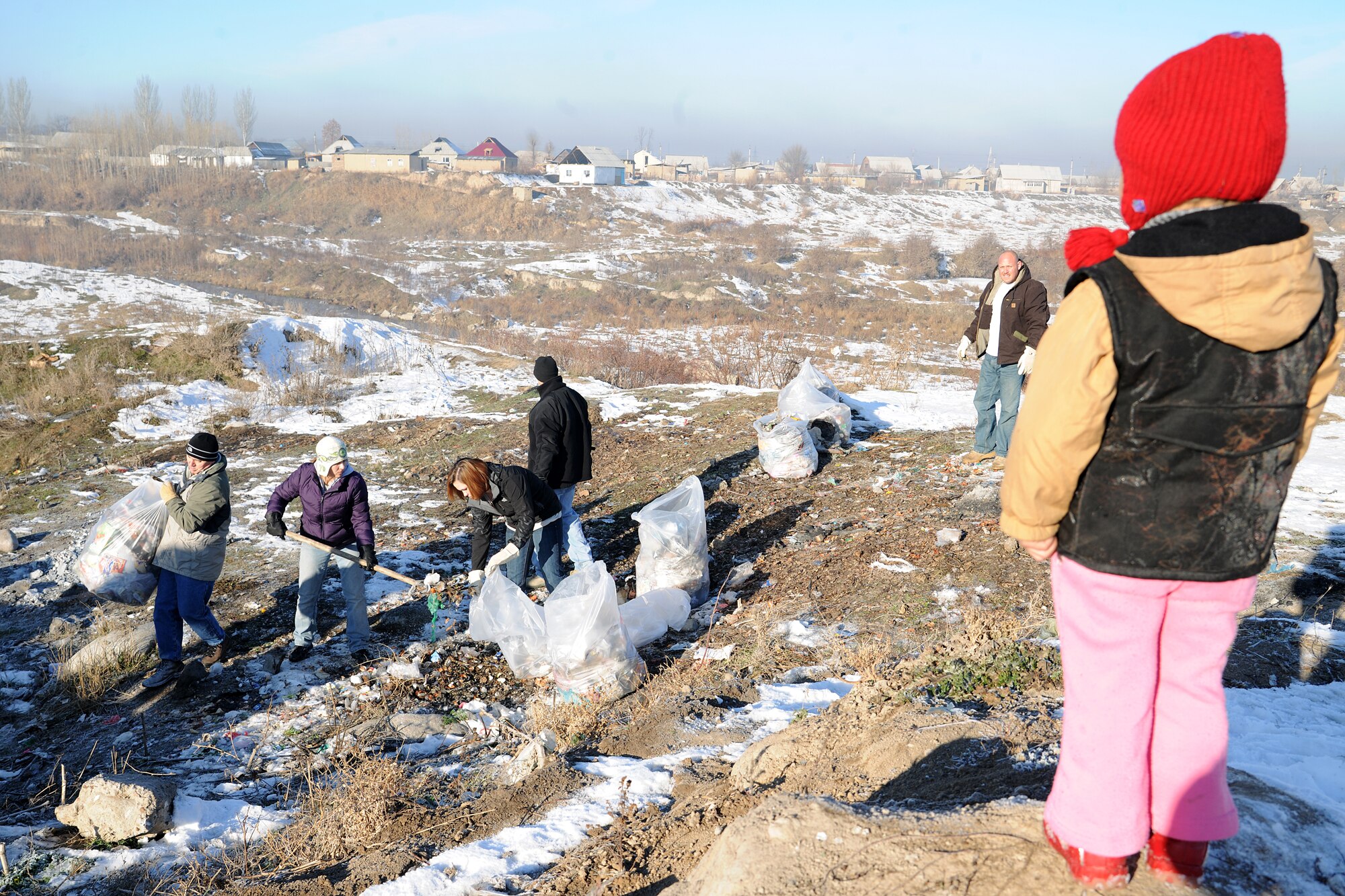 BISHKEK, Kyrgyzstan -  A Kyrgyz child watches on as Airmen from the Transit Center at Manas teamed up with the local government, community residents and Koi-Tosh Non-Commissioned Officer Academy military members for a community clean up. More than 100, 30-gallon bags were filled with trash. The First Four, a professional organization made up of Airmen in the first four junior ranks, organized the event for the Enesay community, just outside Bishkek.  (U.S. Air Force photo/Staff Sgt. Nathan Bevier)