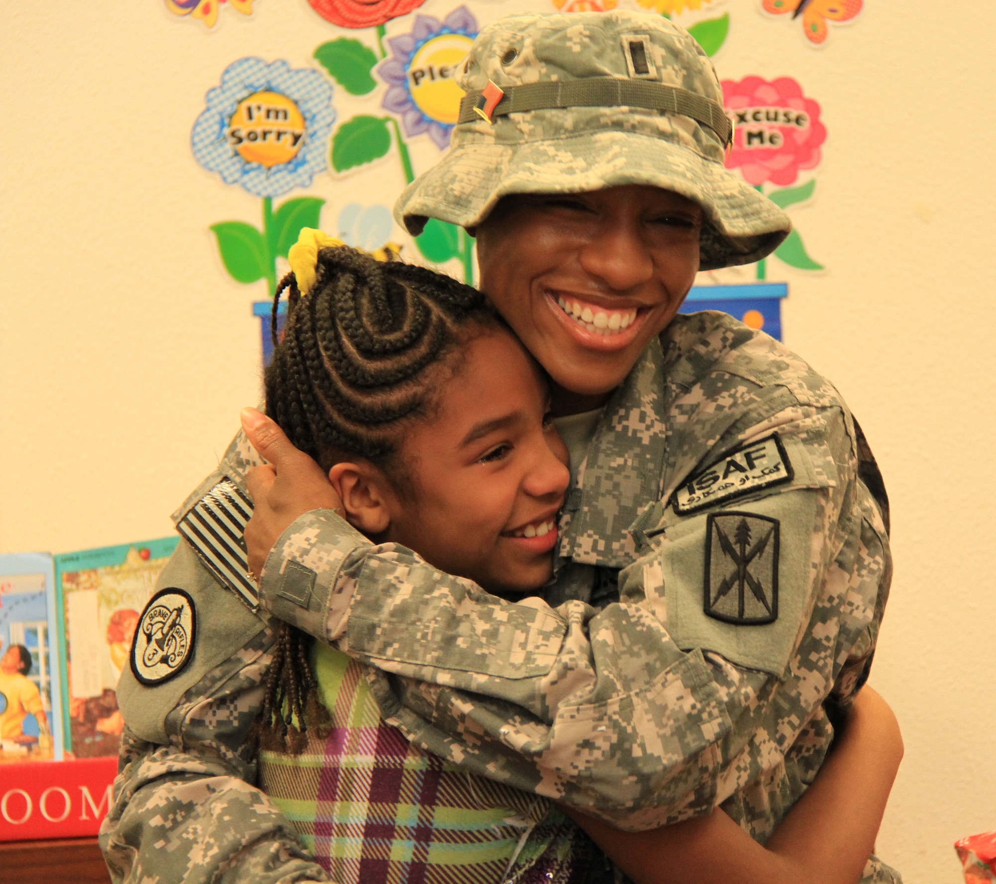 1st Lt. Sharjuan P. Burgos hugs her daughter, Ashliyn, in Ms. Paige Miller's fourth grade class at Kadena Elementary School at Kadena Air Base, after surprising her by coming home a week early, Dec. 13. Burgos was deployed to Afghanistan in May and decided to surprise her daughter for Christmas by returning early for the holiday and jumping out of a giant Christmas gift in the classroom. Burgos plans to spend quality time with her daughter, meeting her friends and teachers before deploying back to Afghanistan immediately after Christmas. (Courtesy photo/ Chip Steitz)