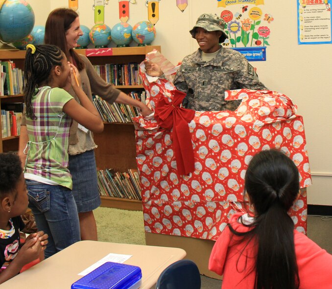 1st Lt. Sharjuan P. Burgos surprises her daughter, Ashliyn by bursting out of a giant Christmas-wrapped box in Ms. Paige Miller's fourth grade class at Kadena Elementary School at Kadena Air Base, Dec. 13. Burgos was deployed to Afghanistan in May and decided to surprise her daughter for the holiday by coming home a week earlier than expected. (Courtesy photo/ Chip Steitz)