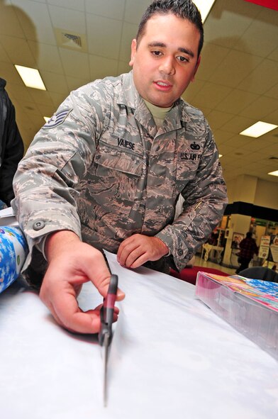 Staff Sgt. Mario Vaiese, 2nd Security Forces Squadron, cuts wrapping paper outside the Base Exchange located on Barksdale Air Force Base, La., Dec. 13. Sergeant Vaiese and members of 2 SFS volunteered their time to wrap presents to raise funds for their holiday party. (U.S. Air Force photo/Senior Airman Joanna M. Kresge)