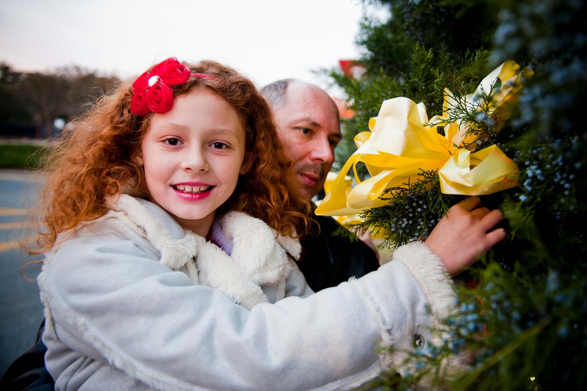 MOODY AIR BASE, Ga. -- Alessa and her father, Master Sgt. Steven Klunk, 23rd Security Forces Squadron operations NCO in charge, attach a yellow ribbon to the base Christmas tree during the Annual Base Tree Lighting and Holiday Parade Dec. 10. Sergeant Klunk said he placed the ribbon for the many deployed Airmen in his unit. (U.S. Air Force photo/Senior Airman Jamal D. Sutter)(RELEASED)