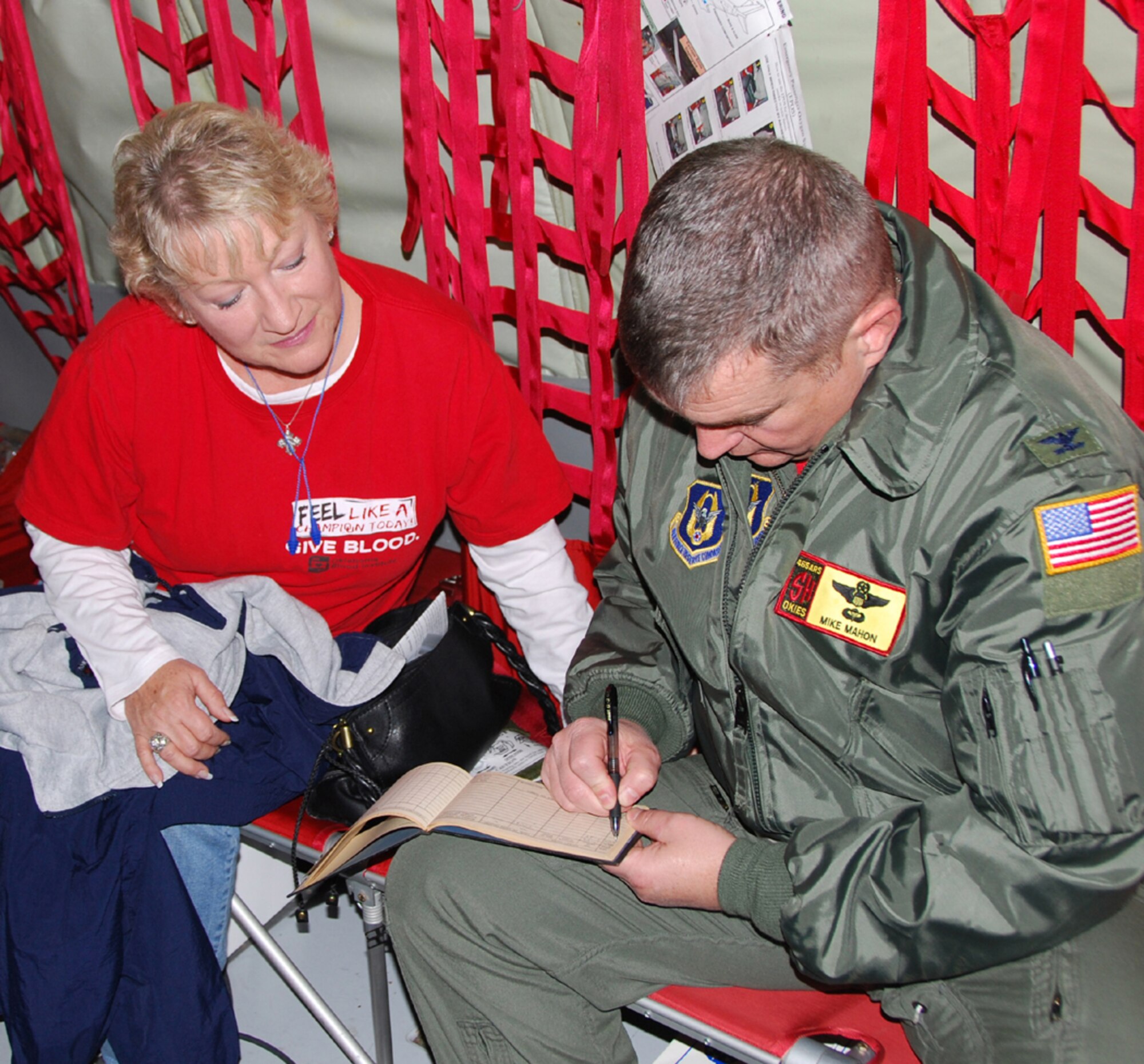 Cecilia Ainsworth,  a Production Management Specialist with the 421st Supply Chain Management Squadron, watches as Col. Michael Mahon, 507th Air Refueling Wing vice commander, adds 2 additional flight hours to her father’s pilot flight hour log book following an employer support orientation flight.  The last previous entry in the log occurred more than 61 years ago.   Ainsworth, the civilian employer of a 507th ARW Air Force Reservist, had been selected to participate in the December 3 flight.  The flights are conducted to show civilian employers the importance of their support for national defense.