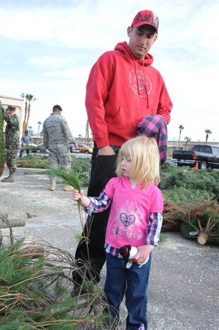 NELLIS AIR FORCE BASE, Nev.-- Staff Sgt. Michael Newman, an F-16 crew chief from the 57th Aircraft Maintenance Squadron, Viper Aircraft Maintenance Unit, looks for a Christmas tree with his 3-year-old daughter Chloe at the base chapel during the Trees for Troops giveaway Dec. 10. Trees for Troops, a charity program sponsored by the Christmas SPIRIT Foundation and FedEx, donated more than 650 Christmas trees to Nellis and Creech Airmen and their families.  (U.S. Air Force photo by Airman 1st Class Matthew Lancaster)