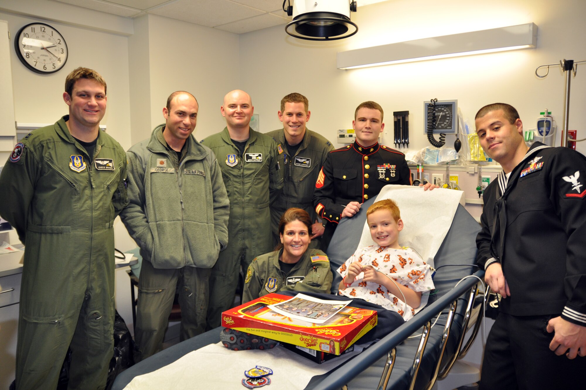 BOARDMAN, Ohio -- Air Force Reserve Capt. Chris Brown, Maj. Joe George, Capt. Bryan Alfredo, Capt. Steve Stroney, U.S. Marine Corps. Reserve Sgt. Terry Wells, U.S. Navy Reserve HM3 Jeffrey Mancino and Air Force Reserve Maj. Michele Mollise, all based at nearby Youngstown Air Reserve Station, Ohio, pose with a patient receiving treatment at Akron Children's Hospital of the Mahoning Valley here, Dec. 9. The child was given toys, military unit patches and an autographed photo of the Air Force Reserve aircrew members posing in front of a C-130 Hercules airplane. This effort, an extension of the 910th Airlift Wing's annual Pilot for a Day program, is designed to reach children who may not be able to visit the air station due to their health condition. U.S. Air Force photo by Maj. Brent J. Davis.