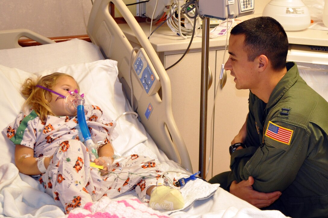 BOARDMAN, Ohio -- Air Force Reserve Capt. Vince Repucci, a C-130H Hercules aircraft navigator with the 757th Airlift Squadron, visits a three-year old patient being treated for pneumonia at Akron Children's Hospital of the Mahoning Valley here, Dec. 9.  He and eight other Air Force Reserve aircrew, Naval and Marine Corps Reservists, based at nearby Youngstown Air Reserve Station, Ohio, took time out of their duty schedules to visit approximately 15 children being treated at the hospital. Each child received toys and an autographed photo of the Air Force Reserve aircrew members posing in front of a C-130 aircraft. This effort, an extension of the 910th Airlift Wing's annual Pilot for a Day program, is designed to reach children who may not be able to visit the air station due to their health condition. U.S. Air Force photo by Maj. Brent J. Davis.