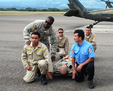 SOTO CANO AIR BASE, Honduras - Army Staff Sgt.Shontal Thompson, flight medic with the 1-228th Aviation Regiment here, coaches firefighters from Honduras and El Salvador, 7 Dec., on proper medical evacuation techniques during the landmark firefighting training exercise known as Central America Sharing Operational Knowledge and Experiences. CENTAM SMOKE is a week-long, quarterly event designed to enhance firefighting capabilities throughout Central America. (U.S. Air Force photo by Capt. John T. Stamm)