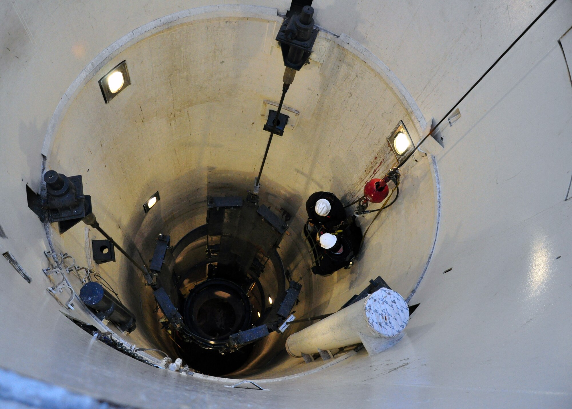 A two-man maintenance crew from Hill Air Force Base, Utah is lowered into place on Dec. 7 to start removing the missile support system from Uniform-1. Once the system is removed it will be sent to Vandenberg Air Force Base, Calif., to undergo repairs, refinish, rechrome and will be repainted. (U.S. Air Force photo by Staff Sgt. Chad Thompson)