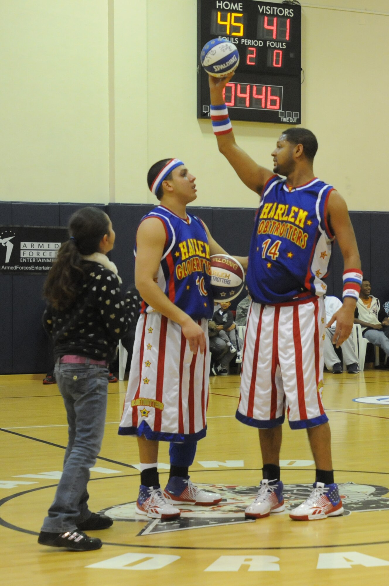 Harlem Globetrotter guards "Blenda" Rodriguez and "Handles" Franklin, give out a free basketball to an Aviano youth at the Dragon Fitness Center Dec. 2. The Globetrotters also gave away free items, such as headbands and wristbands.(U.S. Air Force photo/Airman 1st Class LaVel Sterling)