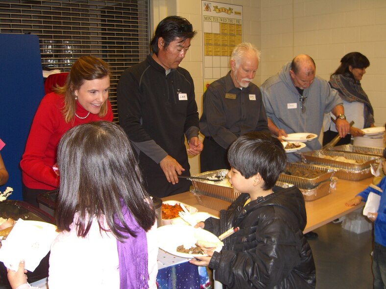 Volunteers serve a holiday meal during the Pearl S. Buck Christmas Party at Osan Dec. 4. (Courtesy photo)
