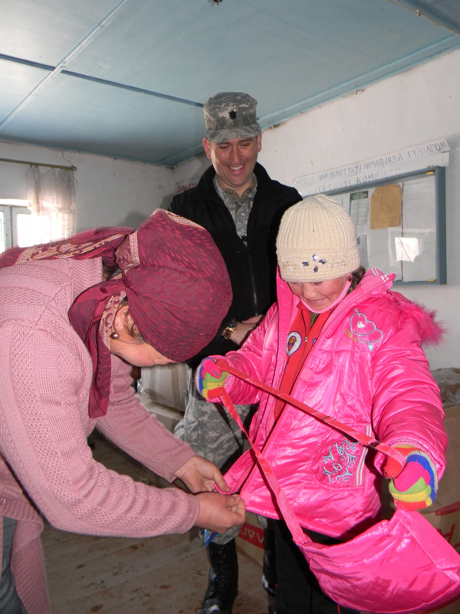 OSH, Kyrgyzstan - Army Lt. Col. Ted Donnelly, Chief of the Office of Military Cooperation at the U.S. Embassy in Bishkek, smiles as a mother fits a blanket to her child during humanitarian assistance project Operation Warm & Dry II Dec. 8.  Transit Center at Manas Airmen teamed up with U.S. Office of Military Cooperation, Joint Distribution Effort, Kyrgyz Ministry of Emergency Situations, Osh Rayon governmental leaders and the Kyrgyz police department to distribute 3,500 pounds of clothing, 1,000 coats and 1,000 blankets to Toguz-Bulak and Sary-Kungoi villages.  (U.S. Air Force photo/Senior Airman Jennifer Archambault)