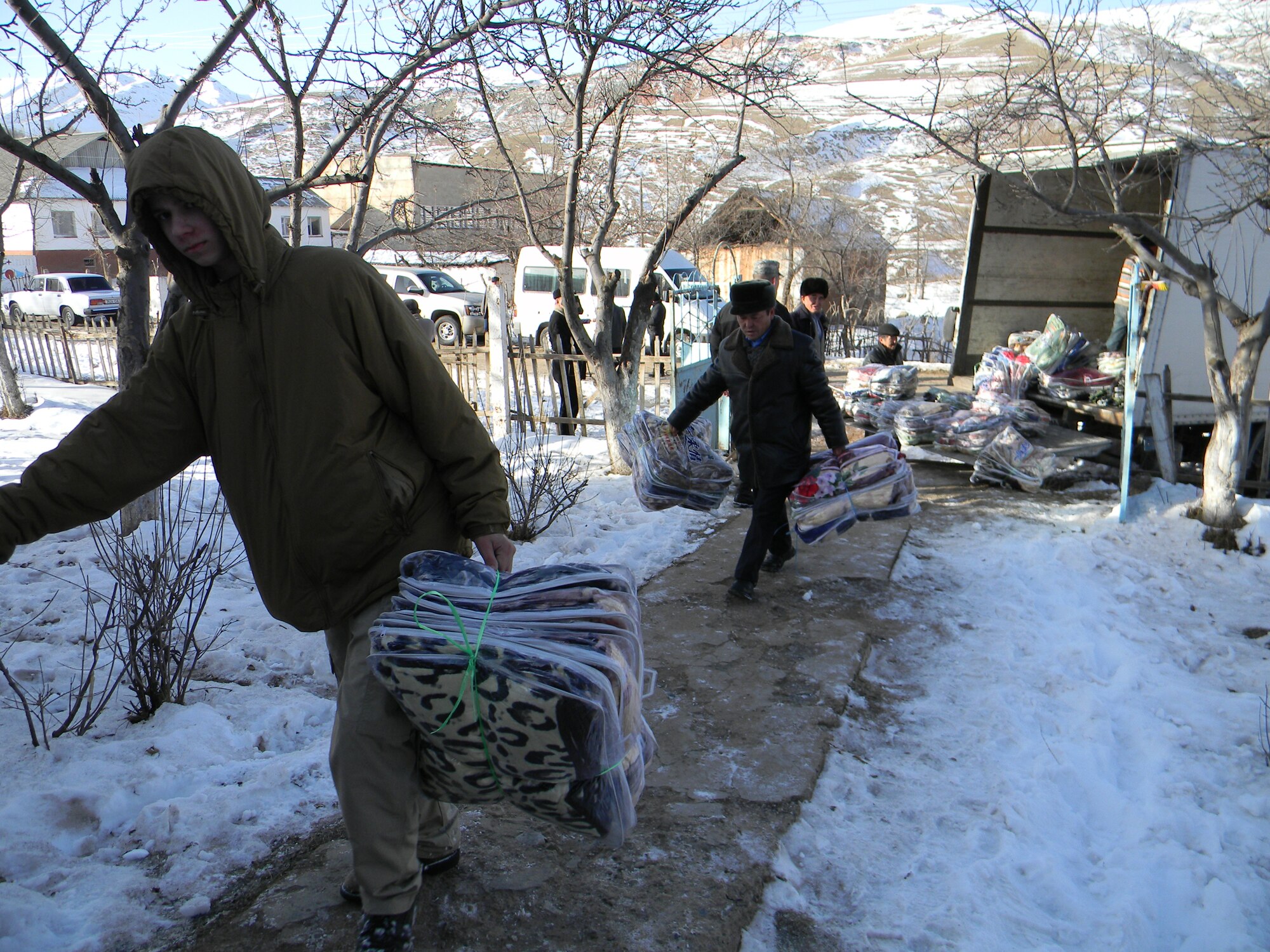 OSH, Kyrgyzstan - Blankets are carried into a facility for distribution to Toguz-Bulak and Sary-Kungoi villages as part of humanitarian assistance project Operation Warm & Dry II Dec. 8.  Transit Center at Manas Airmen teamed up with U.S. Office of Military Cooperation, Joint Distribution Effort, Kyrgyz Ministry of Emergency Situations, Osh Rayon governmental leaders and the Kyrgyz police department to distribute 3,500 pounds of clothing, 1,000 coats and 1,000 blankets.  (U.S. Air Force photo/Senior Airman Jennifer Archambault)