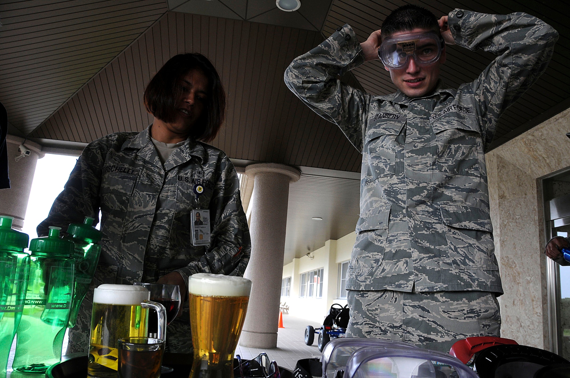Staff Sgt. Amabely Fischelli and Senior Airman Brett Stanbery, both members of the 18th Medical Group, try on various drunk goggles on the display table during an outreach event for the National Drunk and Drugged Driving Prevention Month at Kadena Air Base, Dec. 15. The National Drunk and Drugged Prevention month informs the public of the effects of driving under the influence by providing information and events that allow the public to experience being under the influence. (U.S. Air Force photo/Staff Sgt. Darnell T. Cannady) 