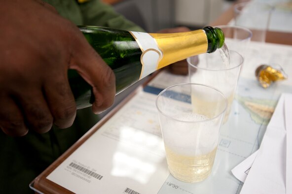 Lt. Col. Brian Hill, 96th Air Refueling Squadron commander, pours drinks from a bottle of champagne to celebrate with aircrew members after completing the squadron's first operational mission Dec. 14 at Joint Base Pearl Harbor-Hickam, Hawaii. During the mission, a 96th ARS KC-135 Stratotanker joined a KC-135 from the Iowa Air National Guard as part of a two-ship formation to refuel two B-52 Stratofortresses on the way to Guam. (U.S. Air Force photo/Staff Sgt. Nathan Allen)