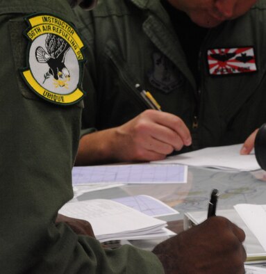 Lt. Col. Brian Hill, 96th Air Refueling Squadron commander and aircraft commander for the squadron's first operational refueling mission, reviews pre-flight planning documents Dec. 14 at Joint Base Pearl Harbor-Hickam, Hawaii. During the mission, a 96th ARS KC-135 Stratotanker joined a KC-135 from the Iowa Air National Guard as part of a two-ship formation to refuel two B-52 Stratofortresses on the way to Guam. (U.S. Air Force photo/Staff Sgt. Nathan Allen)