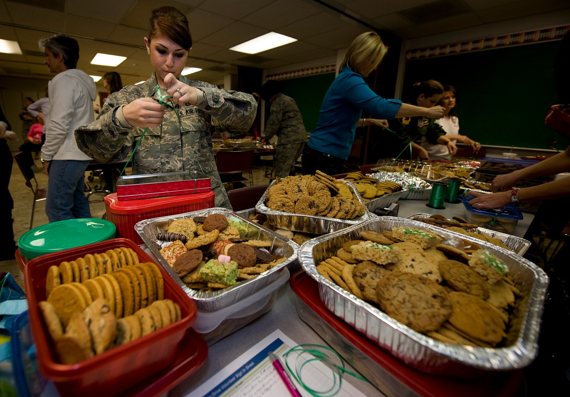 NELLIS AIR FORCE BASE, Nev. -- Airman 1st Class Amanda Kalmykov, 99th Logistics Readiness Squadron equipment specialist, ties ribbons to boxes of cookies during the Annual Cookie Drive Dec. 14. The cookie drive is held during the holidays for single Airmen living in the dorms. (U.S. Air Force photo by Senior Airman Brett Clashman/Released)
