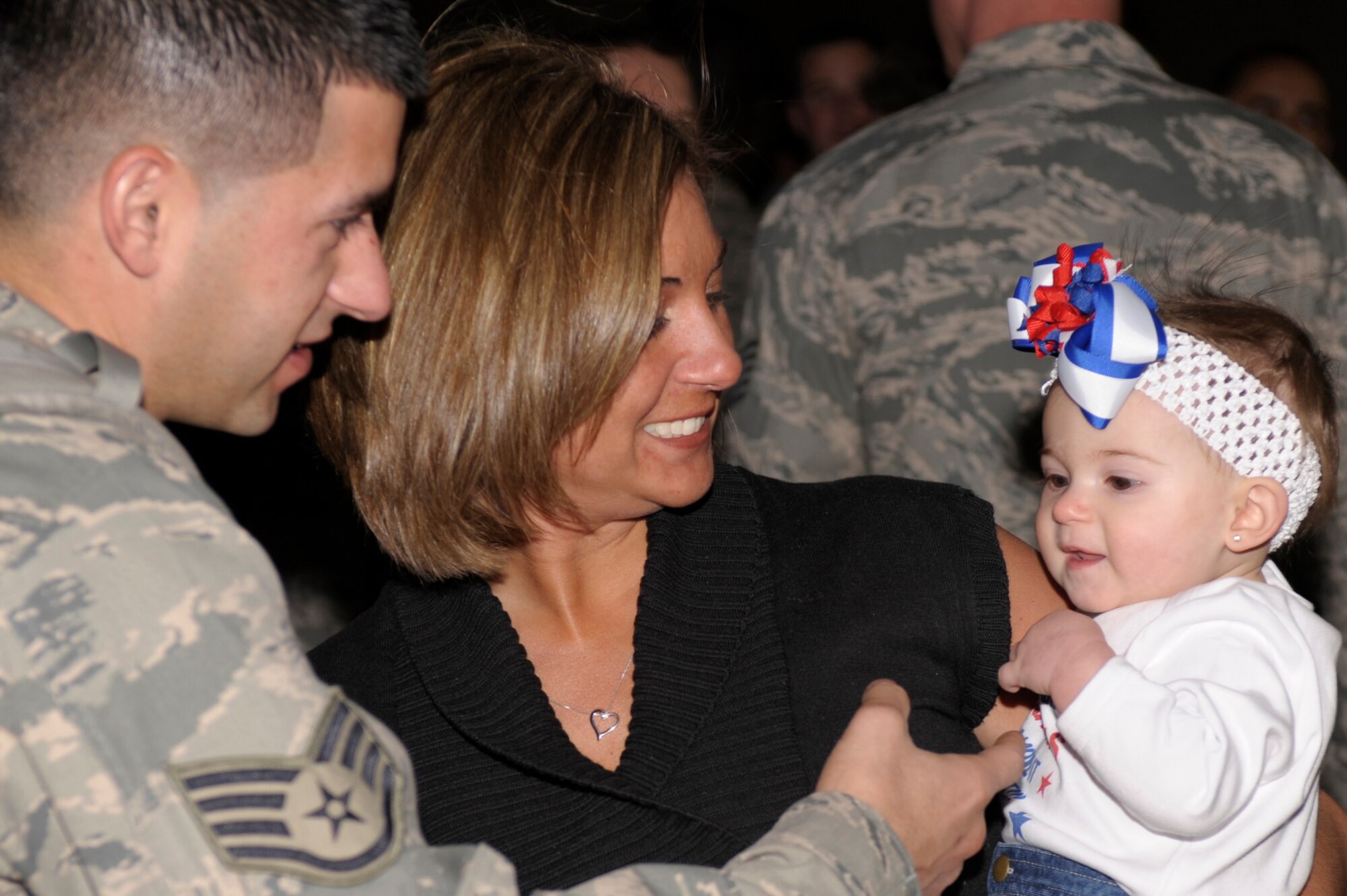 U.S. Air Force Staff. Sgt. Jeremy Puskus, 27th Special Operations Aircraft Maintenance Squadron, hugs his wife Lindsey and greets his daughter Giovanni for the first time outside hanger 196 on Dec. 10. Puksus was one of the Air Commandos who returned from deployment Dec. 10, family and friends gathered in hanger 196 to greet the Airmen as they stepped off the plane. (U.S. Air Force Photo by Airman Ericka Engblom) 