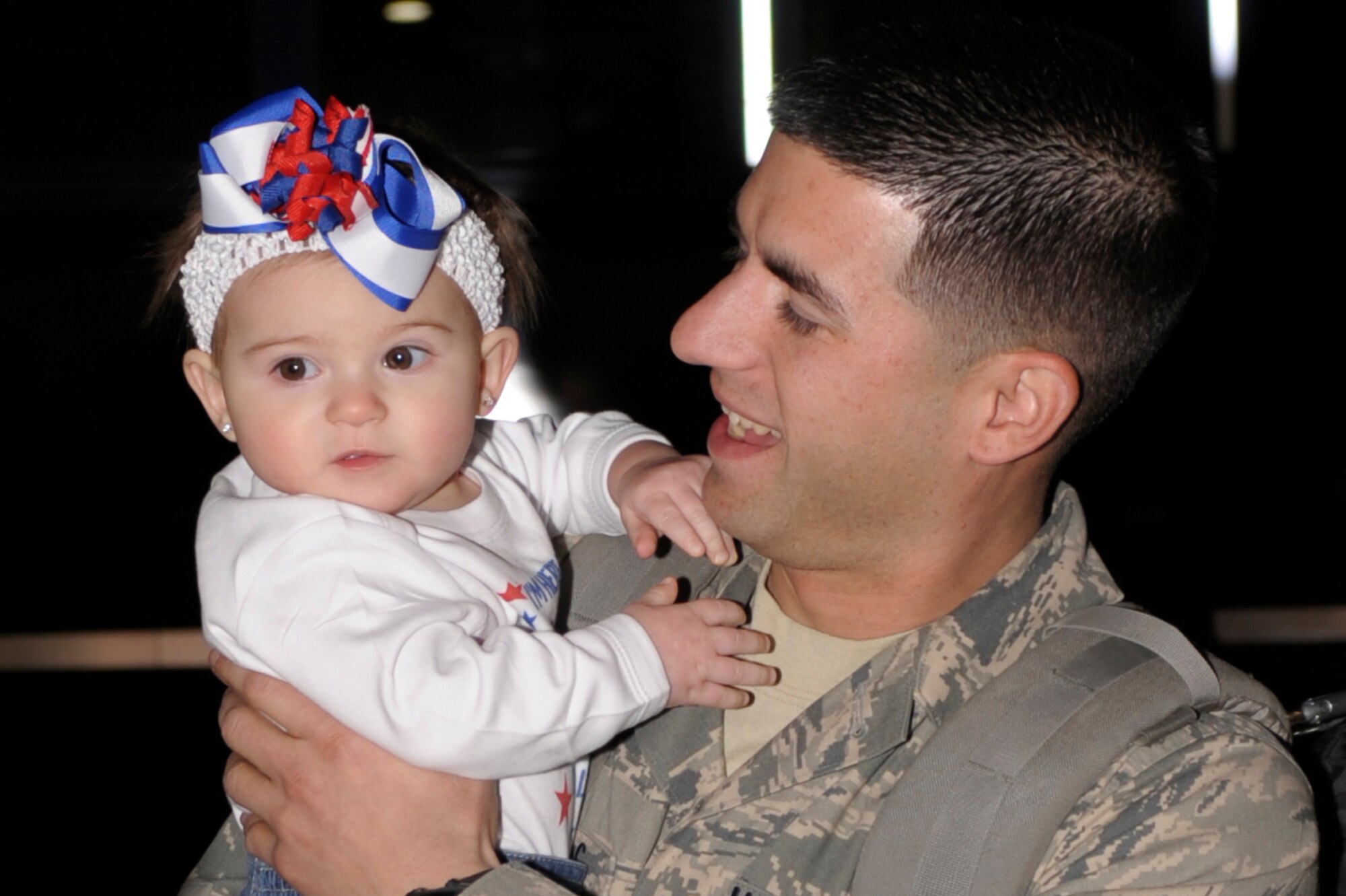 U.S. Air Force Staff. Sgt. Jeremy Puskus, 27th Special Operations Aircraft Maintenance Squadron, holds his daughter Giovanni for the first time after returning from deployment, outside hanger 196 Dec. 10. Family and friends of returning Air Commandos gathered in hanger 196, prior to the plane landing, to welcome them home. (U.S. Air Force Photo by Airman Ericka Engblom)
