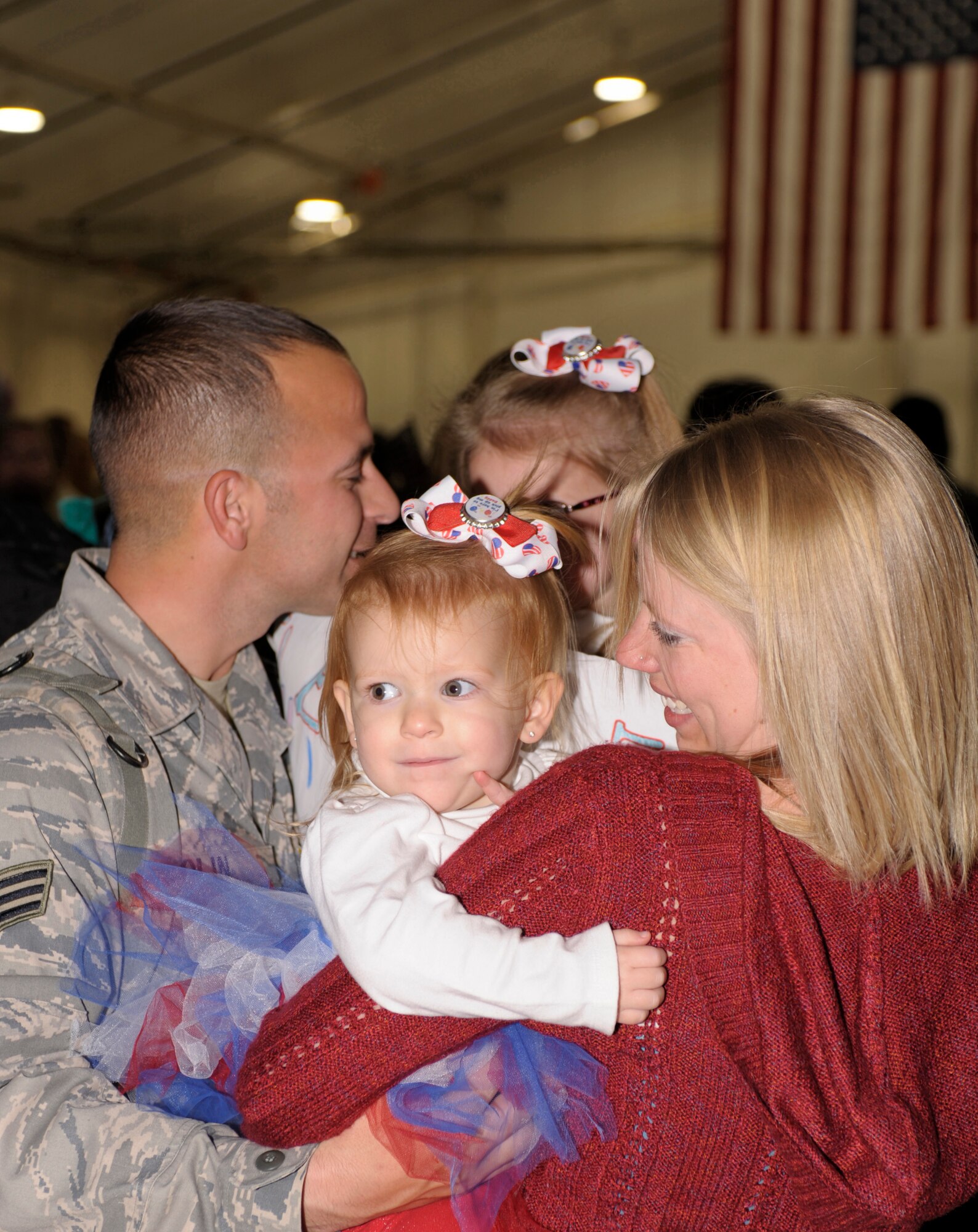 U.S. Air Force Senior Airman Lesley Olin, 27th Special Operations Wing, reunites with his family Tasha, Delanie  and Kinlee outside of hanger 196 on Dec. 10. Family and friends gathered at hanger 196 in order to greet their redeployed Air Commandos. (U.S. Air Force photo by Airman Ericka Engblom)