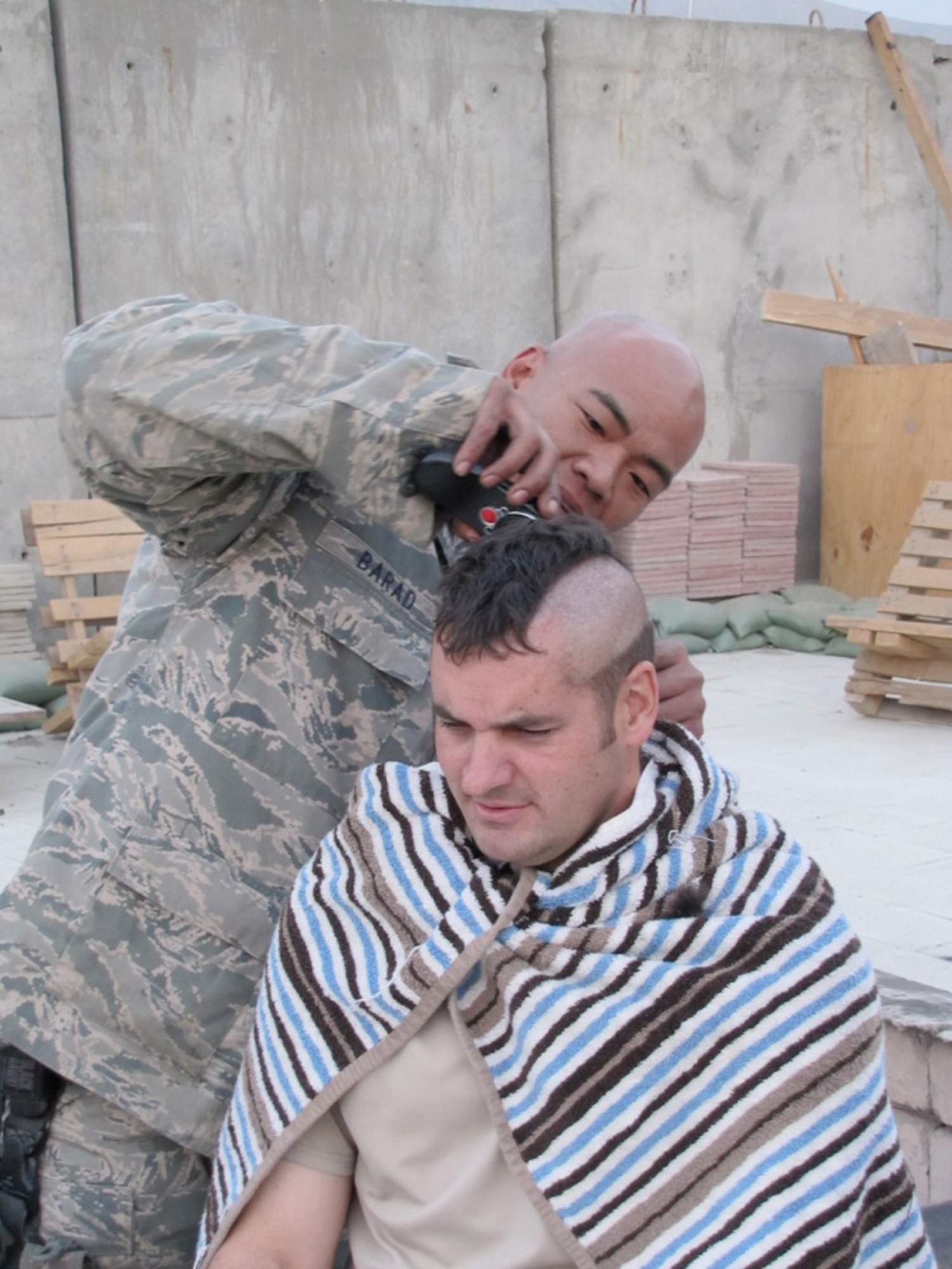 Tech. Sgt. Arthur Barad shaves Senior Master Sgt. Bubba Beason's head so he could participate in a group photo for Lyla, a cancer patient and the St. Jude's Childrens Research Hospital Dec 6, 2010. Sergeant Barad is a C-27 NATO Air Training Command - Afghanistan adviser. (U.S. Navy photo/Petty Officer Jared Walker)
