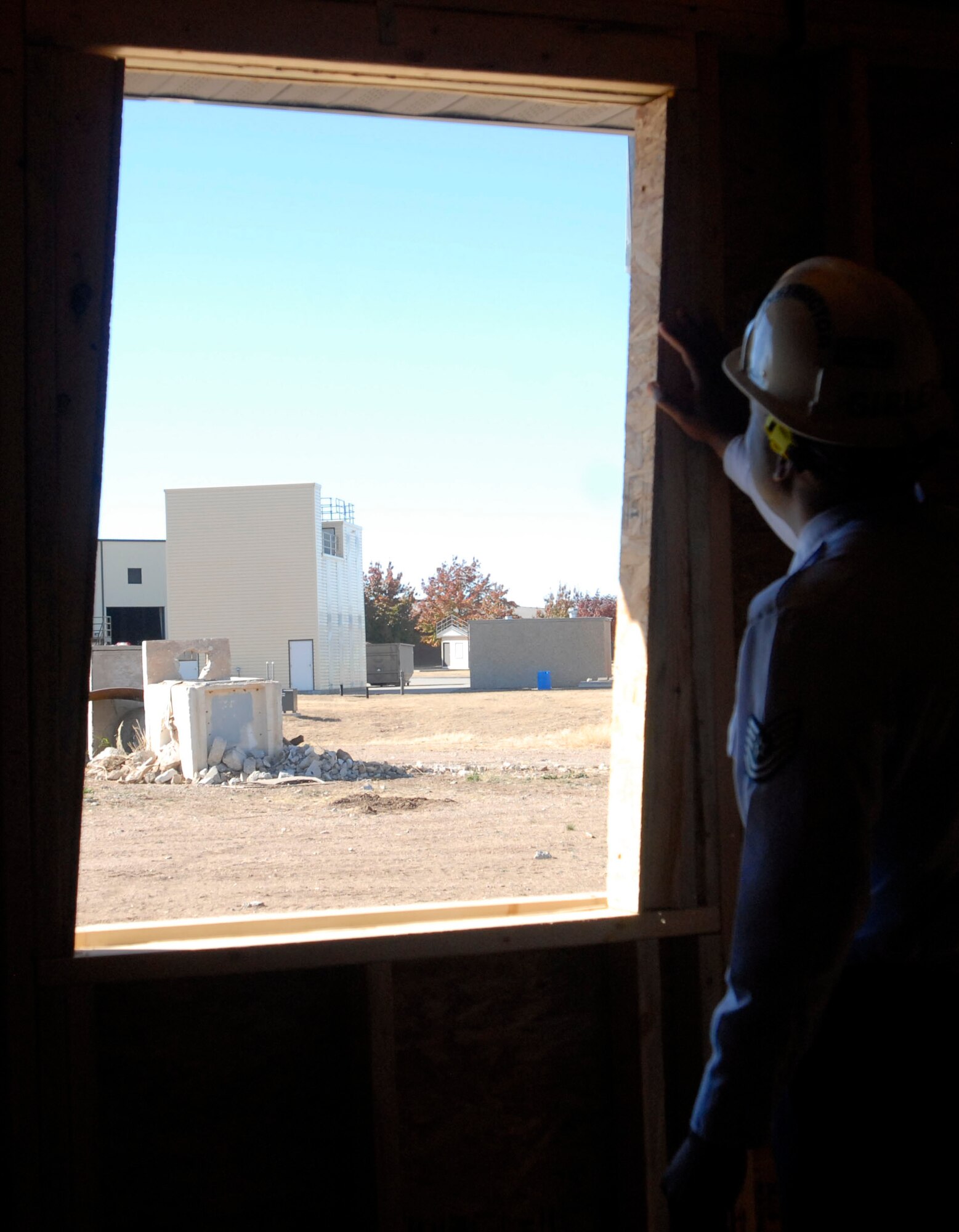 GOODFELLOW AIR FORCE BASE, Texas-- Tech. Sgt. Travis Girley, Rescue Technition I course NCOIC, examines a slanted window frame in the Fire Academy's new lightweight structural trainer here Dec 13. The trainer simulates the effects of high pressure on a building's support structure and also features cracked and bulging walls. (U.S. Air Force photo/Airman 1st Class Jessica D. Keith) 