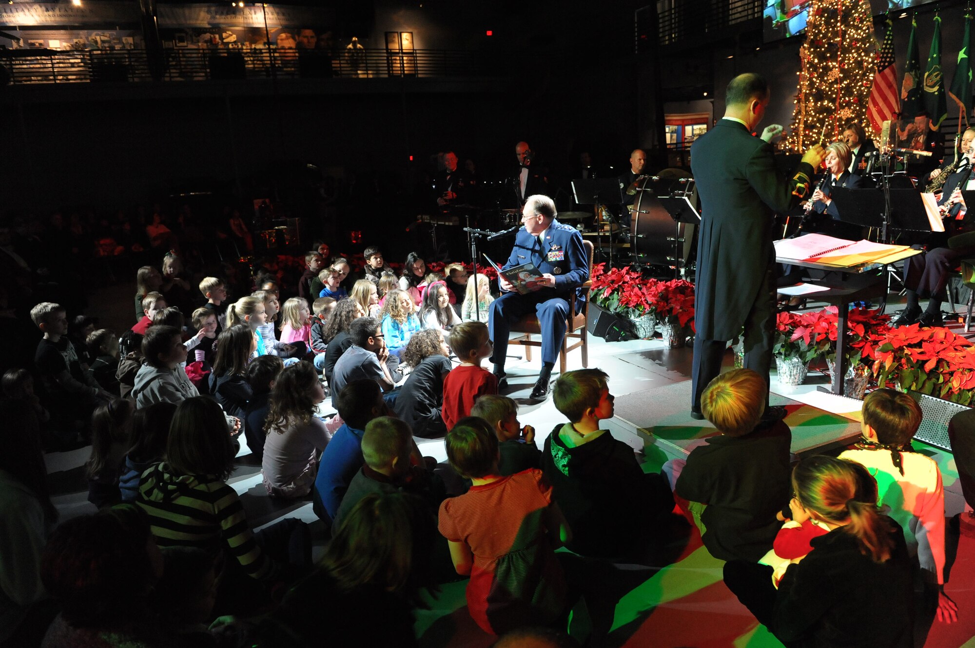 Lt. Gen. Charles E. Stenner, Jr., commander of Air Force Reserve Command, reads "The Night Before Christmas" to children gathered at the Museum of Aviation for the Band of the U.S. Air Force Reserve's annual Holiday Concert, Dec. 9, 2010. Maj. Donald Schifield, band commander and conductor, leads the Emmy-nominated concert band while General Stenner narrates. More than 800 community members attended the event. (U.S. Air Force photo/Raymond Crayton, Jr.)