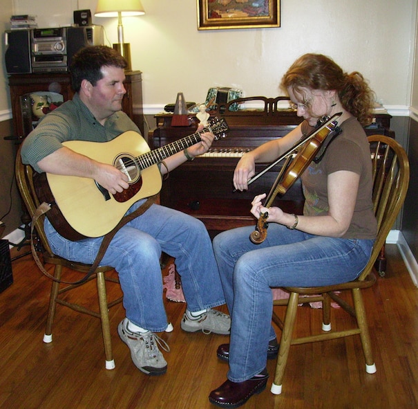 Jeff Haley plays a guitar while his wife Becky plays her fiddle during a practice session at their home. (Photo provided)