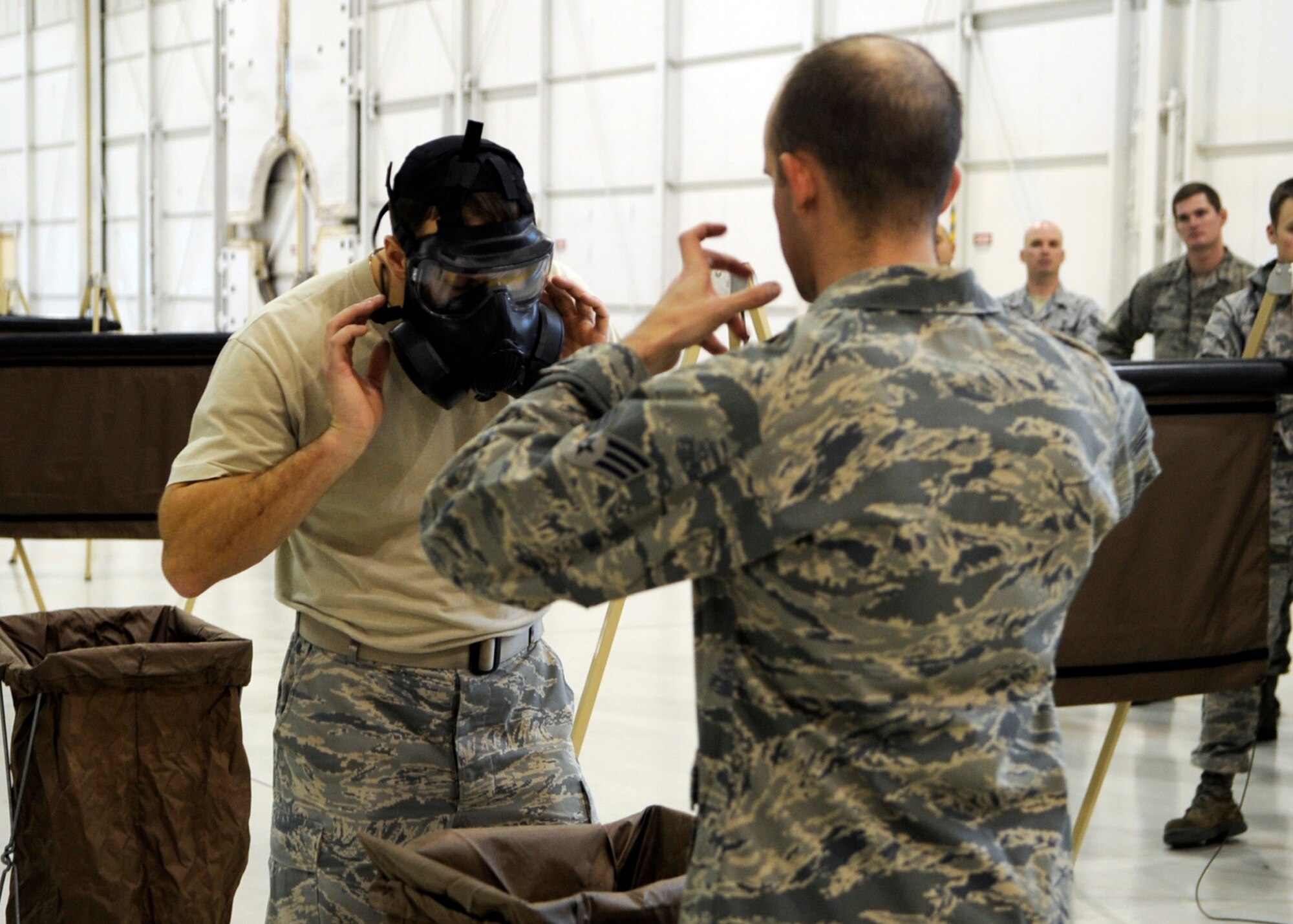 MOUNTAIN HOME AIR FORCE BASE, Idaho -- Senior Airman David Kandziolka, 366th Civil Engineer Squadron, demonstrates how to properly remove his “contaminated” gas mask to Staff Sgt. Troy Zimmerman, also from the 366th CES, during the Ability to Survive and Operate Rodeo training here Dec. 13 in Hangar 1331. The purpose of the ATSO Rodeo was to increase the critical real-world and Phase II ATSO skills through combined academic and practical stations. (U.S. Air force photo by Senior Airman Angelina Drake)