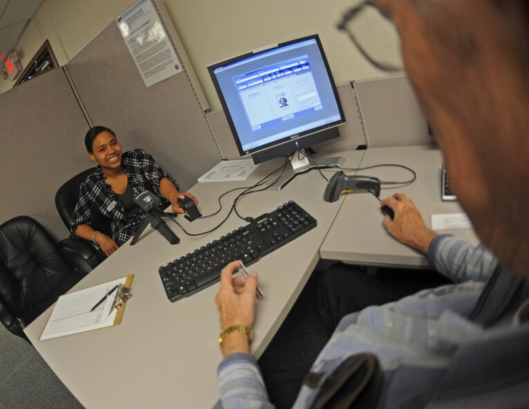 BARKSDALE AIR FORCE BASE, La. -  Ms. Tia Morris, 2nd Force Support Squadron, places her finger on a scanner to register her identification card with the defense biometric identification system at Barksdale Air Force Base, La., on Dec. 14. Mr. Al Watts, 2nd Security Forces Squadron, verifies the information on an individual's card with the database. DBIDS is an enhanced security device used to better secure the base by identifying individuals attempting to gain access to the installation. (U.S. Air Force photo/Senior Airman Alexandra M. Boutte) (RELEASED)