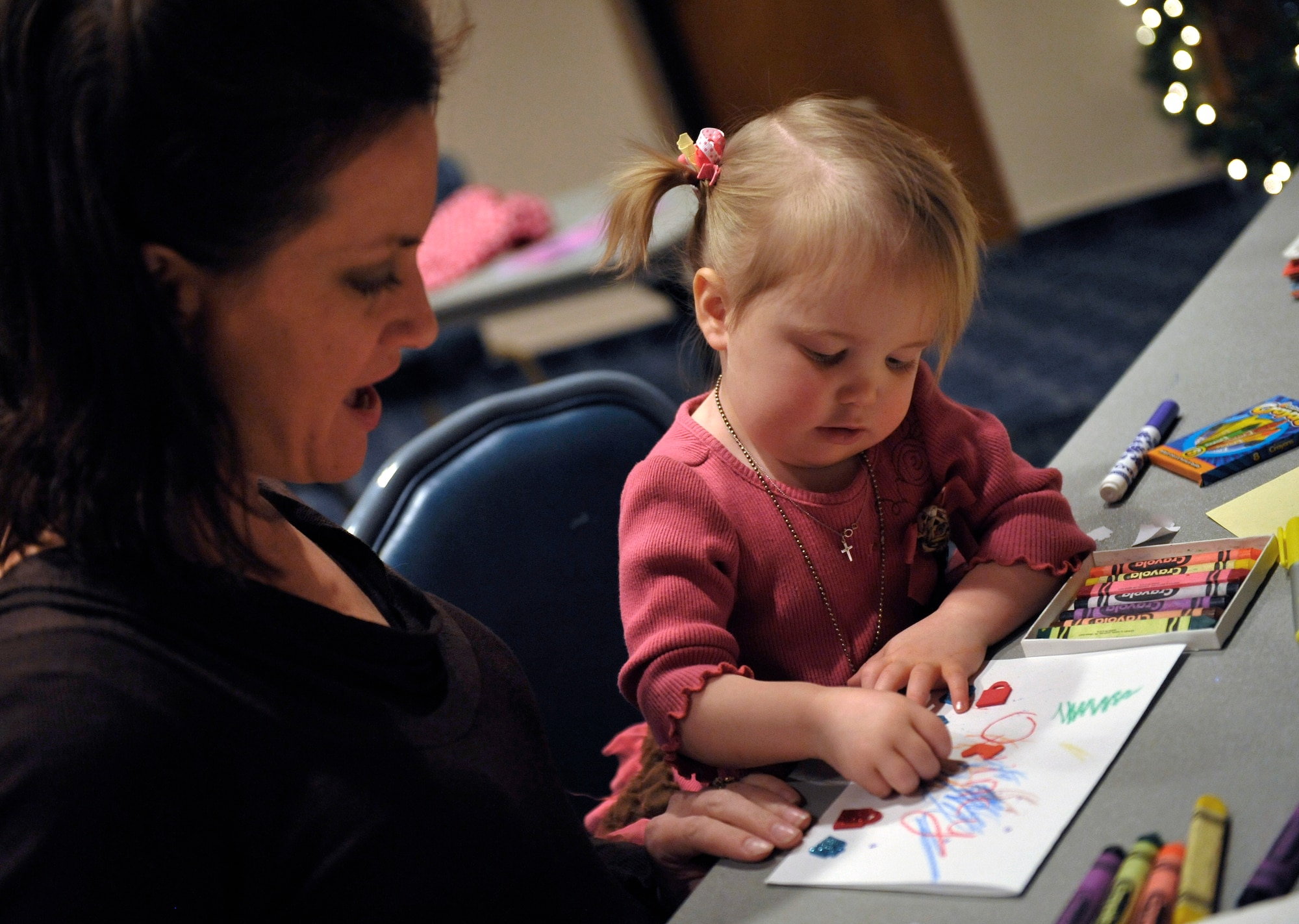HOLLOMAN AIR FORCE BASE, N.M. -- Randy Baker, wife of Tech. Sgt. Scott Baker, makes a Christmas card with their daughter, Quincy, to send to her deployed father during the Jingle Bell Banquet and Deployment Expo Dec. 7, 2010. Families who attended the banquet were able to send their remote, extended temporary or deployed family member a picture on a pillowcase, enjoy a free dinner, play games and win prizes. Several organizations from the 49th Wing were also there to help answer any questions on the services provided for families with deployed members. Sergeant Baker is an Explosive Ordinance Disposal technician with the 49th Civil Engineer Squadron. (U.S. Air Force photo be Senior Airman Veronica Stamps/Released)
