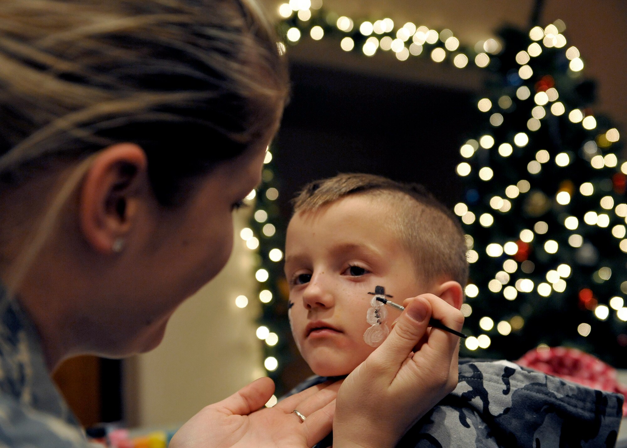 HOLLOMAN AIR FORCE BASE, N.M. -- Senior Airman Melissa Smith, 49th Aerospace Medicine Dental Squadron, paints a snowman on Wyatt Braswell, son of Staff Sgt. Daryle Braswell, 49th Civil Engineer Squadron, during the Jingle Bell Banquet and Deployment Expo Dec. 7, 2010. The Desert Sands enlisted club hosted a free dinner for all families with military members who are remote, extended temporary duty location or deployed. Several organizations from the 49th Wing were also there to help answer any questions on the services provided for families with deployed members. (U.S. Air Force photo by Senior Airman Veronica Stamps/Released)