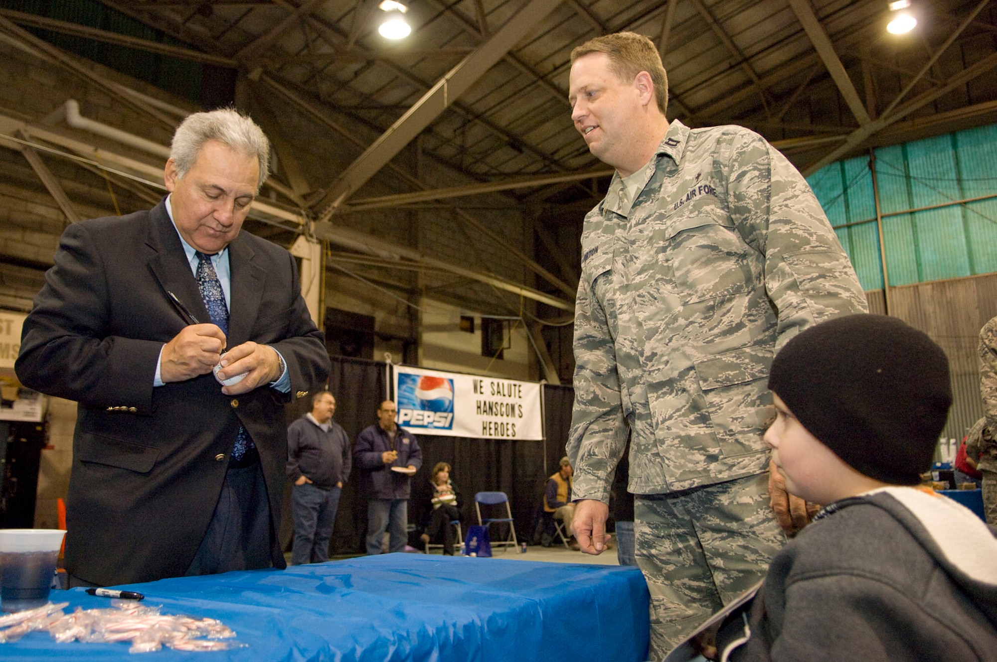 HANSCOM AIR FORCE BASE, Mass. – Red Sox legend Rico Petrocelli (right) signs a baseball for Chaplain Michael Gorton and his son, Jakob, after the Heroes Homecoming ceremony in the Aero Club Hangar on Dec. 10. More than 50 Hanscom personnel who have returned from deployments in the past six months and their families were honored during this pep rally-style event. (U.S. Air Force photo by Mark Wyatt)