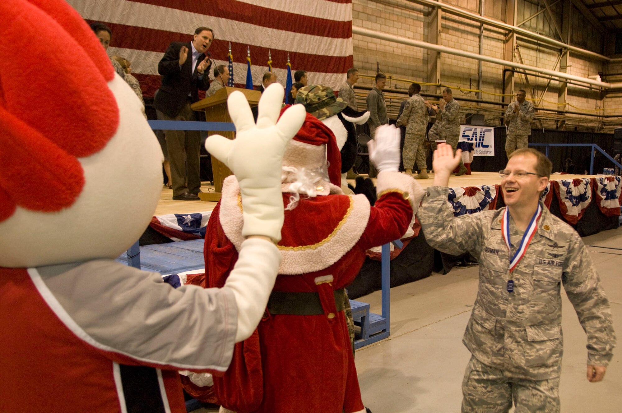 HANSCOM AIR FORCE BASE, Mass. – Maj. Robert E. Duman (right) gives high fives to Santa Claus and Blaze, the Boston Blazers lacrosse team mascot, during Heroes Homecoming in the Aero Club Hangar on Dec. 10. More than 50 Hanscom personnel who have returned from deployments in the past six months and their families were honored during this pep rally-style event. (U.S. Air Force photo by Mark Wyatt)