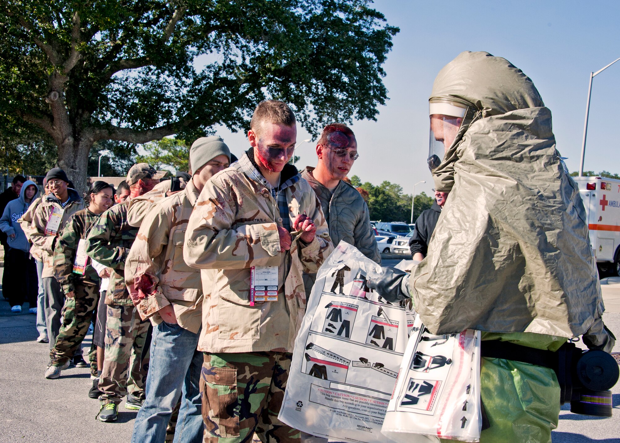 A 96th Medical Group Airman in chemical gear hands out contamination bags for the simulated victims clothing prior to them entering the decontamination tent.  The base's Chemical Biological Nuclear Explosive exercise tested Eglin's first responders such as security forces and fire department as well as the medical group's emergency technicians.  96th MDG Airmen set up a decontamination tent to process the victims through before providing detailed medical attention.   (U.S. Air Force photo/ Samuel King)