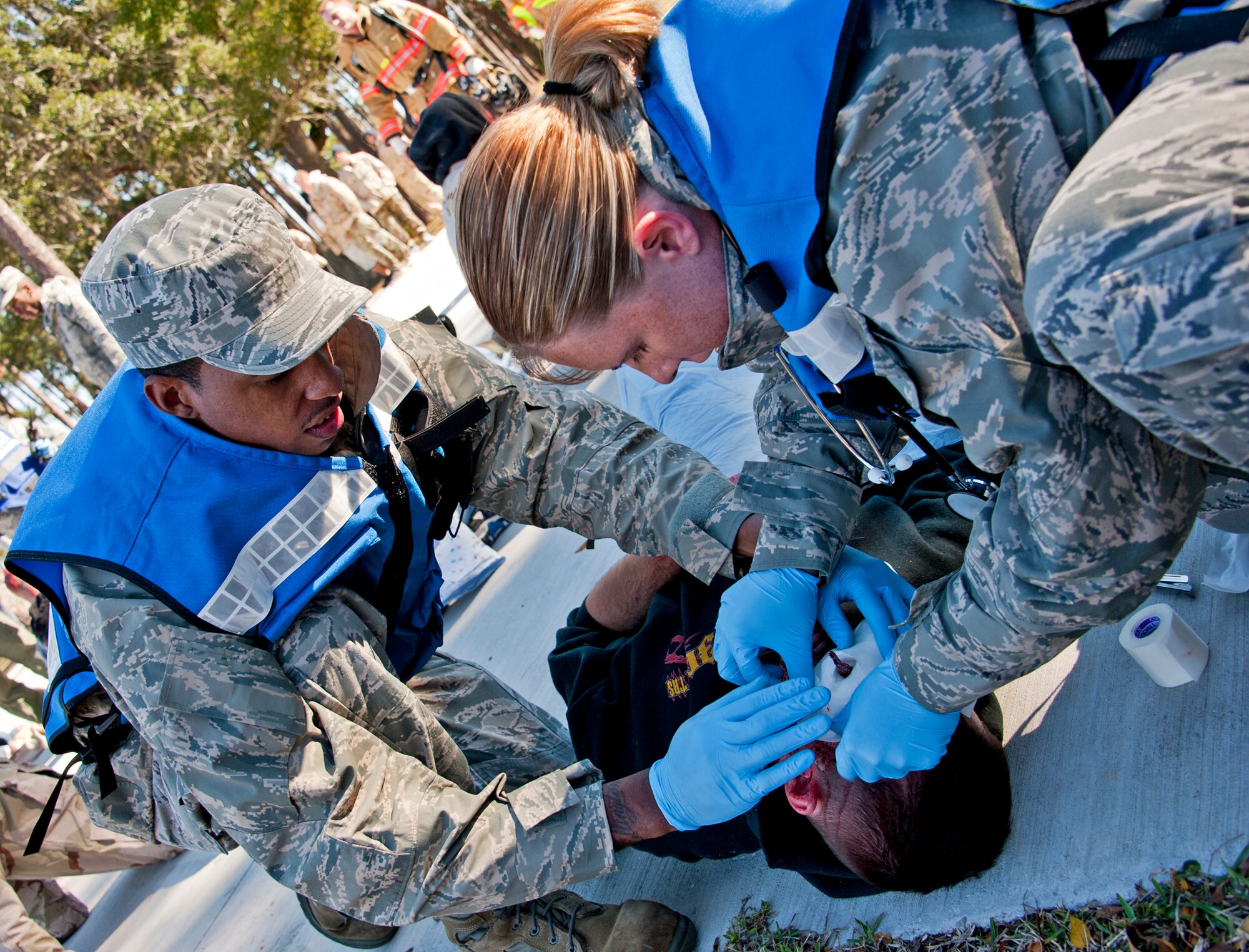 Senior Airman Charles Ellington and Staff Sgt. Vaulta Hanni, 96th Medical Group, dress a “victim’s” head wound outside the contaminated zone at Post'l Point Dec. 1.  The base's Chemical Biological Nuclear Explosive exercise tested Eglin's first responders such as security forces and fire department as well as the medical group's emergency technicians.  96th MDG Airmen set up a decontamination tent to process the victims through before providing detailed medical attention.   (U.S. Air Force photo/ Samuel King)
