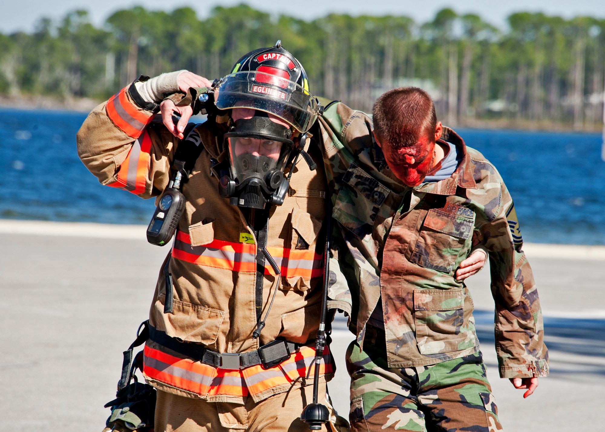 Christopher Hoffman, 96th Civil Engineer Squadron firefighter, helps a “victim” out of the contaminated zone at Post'l Point Dec. 1.  The base's Chemical Biological Nuclear Explosive exercise tested Eglin's first responders such as security forces and fire department as well as the medical group's emergency technicians.  96th Medical Group Airmen set up a decontamination tent to process the victims through before providing detailed medical attention.   (U.S. Air Force photo/ Samuel King)