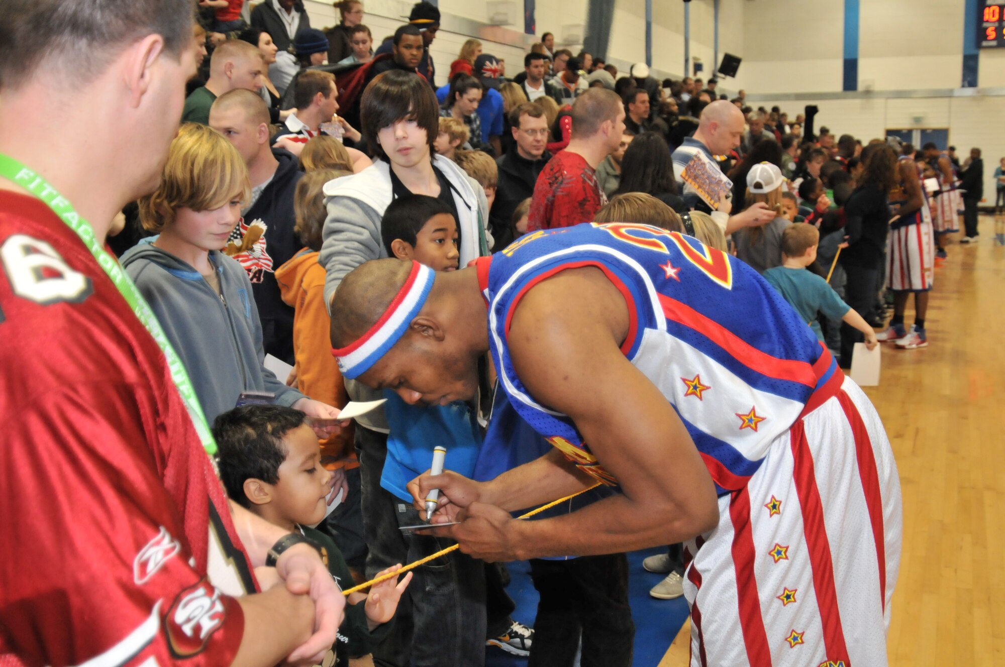 ROYAL AIR FORCE LAKENHEATH, England -- “Zeus” Stewart of the Harlem Globetrotters signs autographs at the Sports & Fitness Center on Dec. 12. The Globetrotters had just won a game against the Washington Generals with their unique blend of skills and comedy. (U.S. Air Force photo/Senior Airman David Dobrydney)