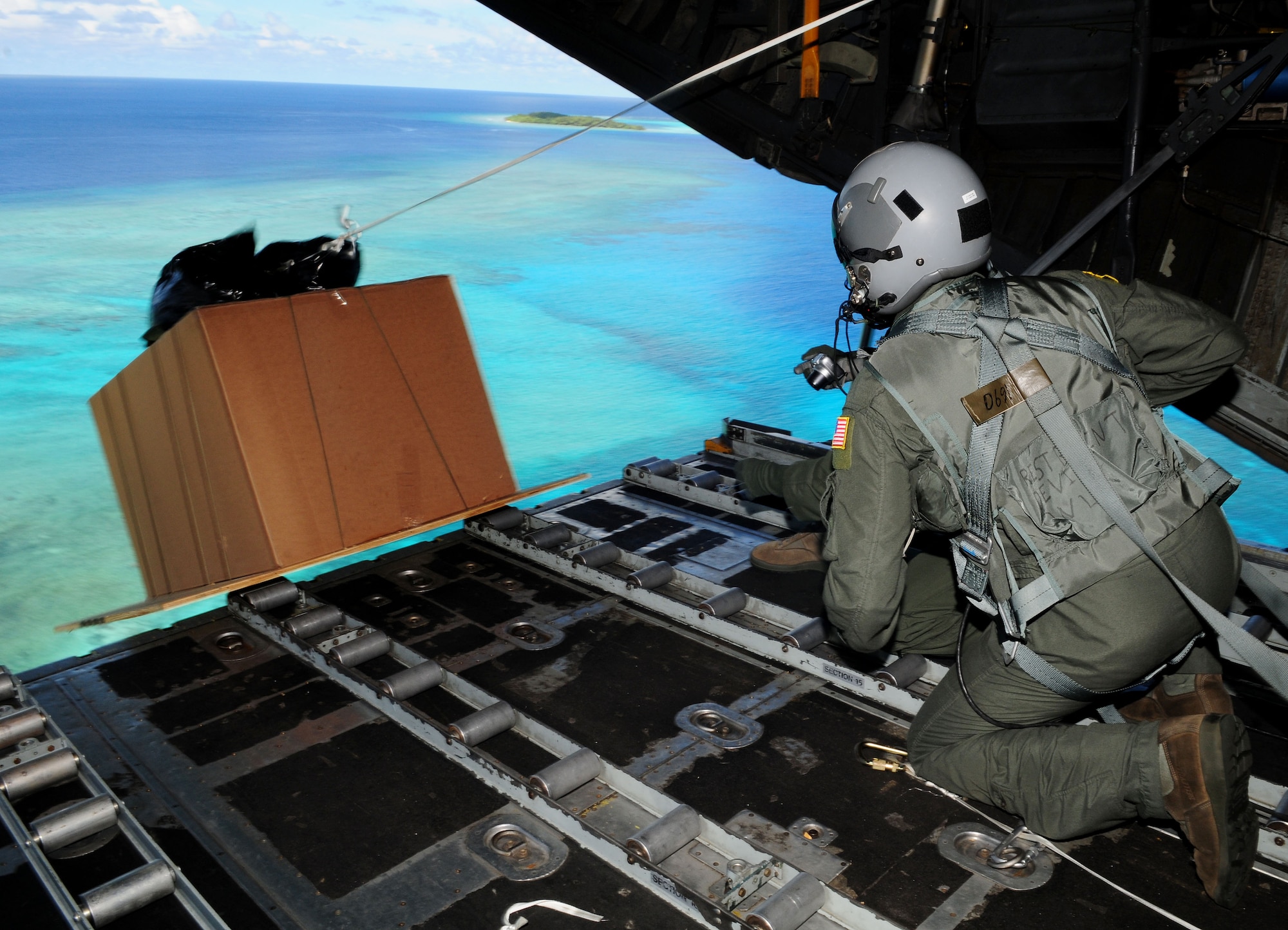 Senior Airman Joseph Doria, 36th Airlift Squadron loadmaster from Yokota Air Base, Japan, and Capt. Stanley Kimball, 36th Airlift Squadron flight surgeon, watch after pushing a box of humanitarian assistance goods out of a U.S. Air Force C-130 Hercules, call sign ?Santa 23? to its drop-zone in Yap Islands during Operation Christmas Drop, Dec. 14. This year more than 60 boxes will be dropped to 55 Island weighing in at more than 20,000 pounds.(U.S. Air Force photo by Senior Airman Nichelle Anderson)