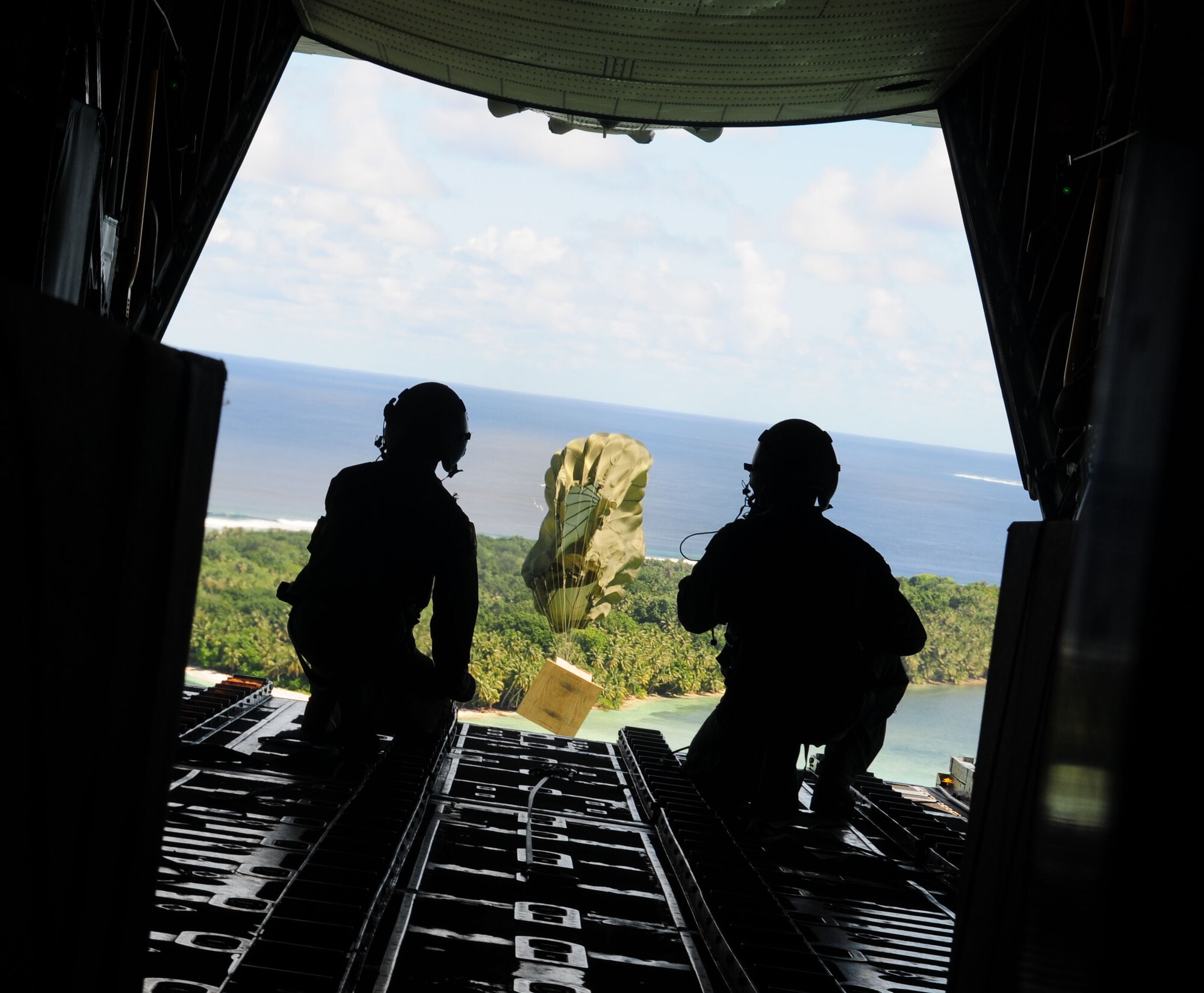 Airmen from the 36th Airlift Squadron, Yokota Air Base, Japan, watch as the parachute deploys and a box of humanitarian goods travels to the Yap Islands below during Operation Christmas Drop, Dec. 14. Operation Christmas Drop is the Air Force?s longest-running humanitarian which began in 1952. What started as a WB-50 aircrew returning to Guam on its final flight before Christmas has turned into the longest running humanitarian campaign in the history of the U.S. Air Force and the entire world. (U.S. Air Force photo Senior Airman Nichelle Anderson)
