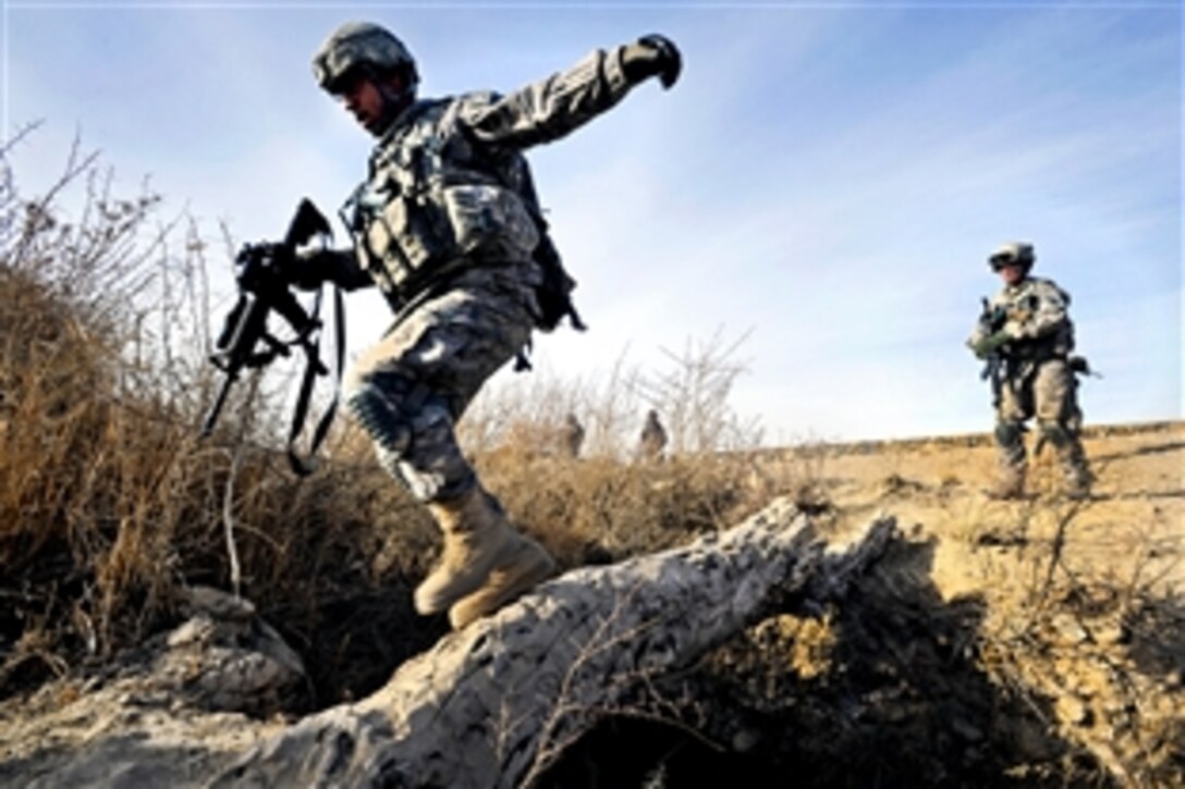U.S. Air Force Staff Sgt. Kevin Flenoury uses a fallen tree to cross a canal during a mission to Khwazi village, Afghanistan, Dec. 14, 2010. Flenoury, assigned to Provincial Reconstruction Team Zabul, visited the village to survey a site for a future well project.