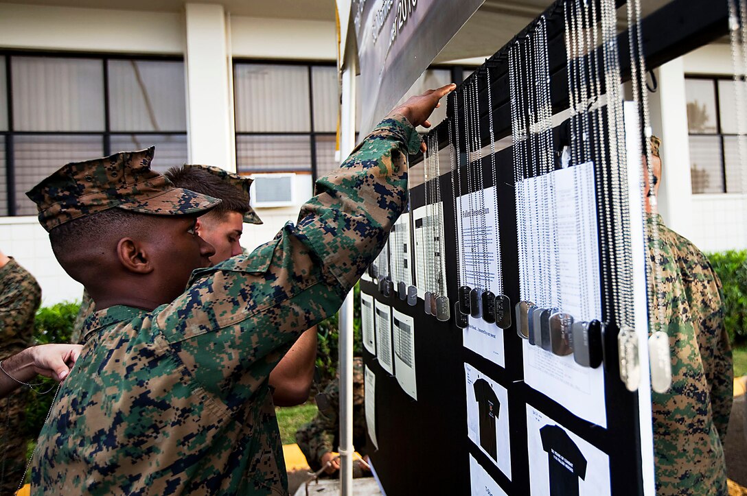 Cpl. Hilary Dalson, an amphibious assault vehicle crew chief, Combat Assault Company, 3rd Marine Regiment, hangs the dog tags of fallen Marines and sailors from 3rd Marine Regiment before the Fallen Heroes Run on Marine Corps Base Hawaii, Dec. 14, 2010. Since 2004, 116 Marines and sailors from 3rd Marine Regiment have been killed during operations in Afghanistan and Iraq. On Dec. 14 and 15, teams of at least two Marines or sailors in combat boots and camouflage trousers ran a 2-mile evolution 116 times — one for each fallen hero. The route took them from the 3rd Marine Regiment headquarters building to the Pacific War Memorial here and back.